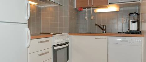 Een koelkast, een magnetron, een vaatwasser, kookgerei, borden en bestek