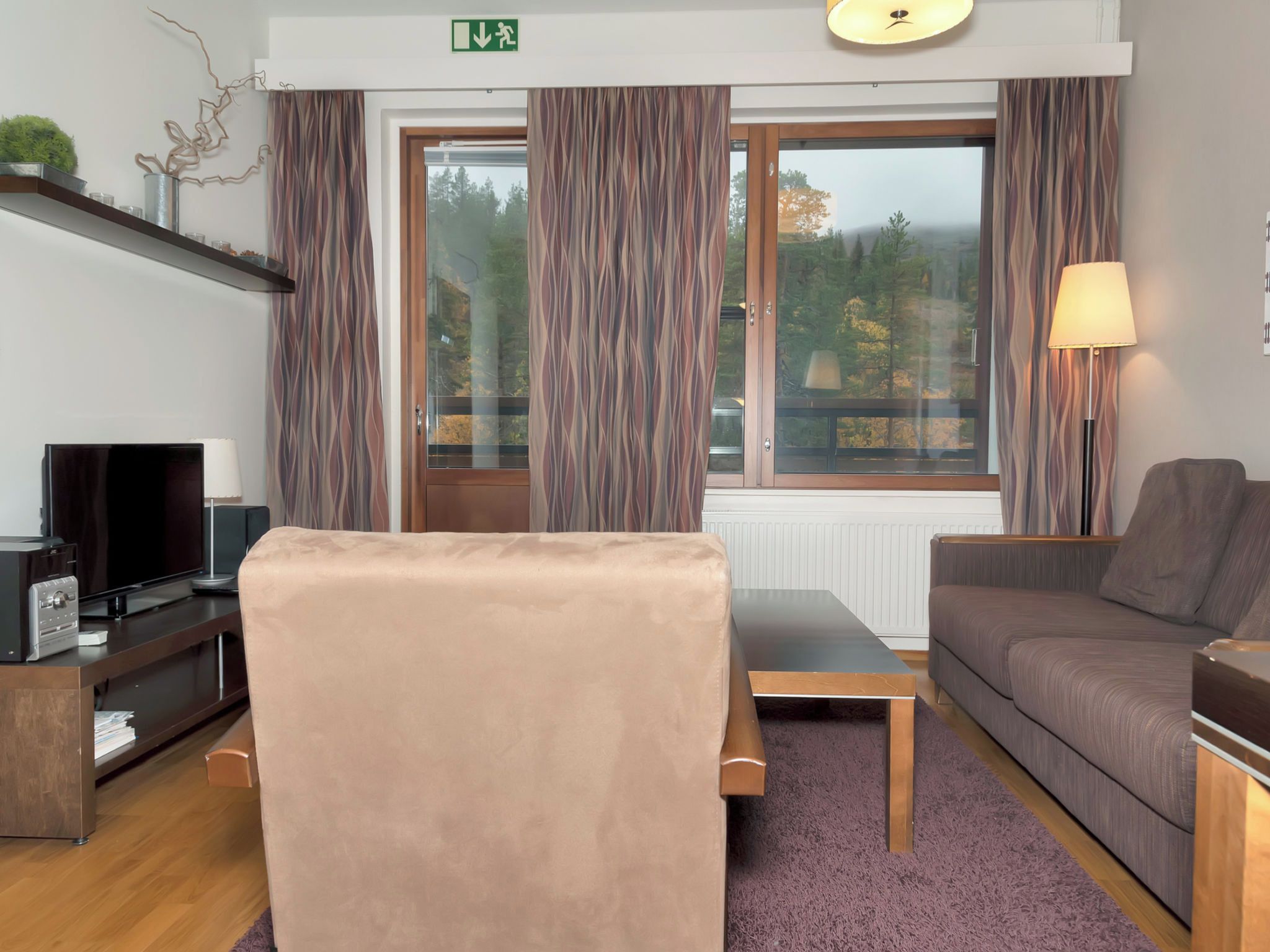 A modern living room with a sofa, a TV, and a lamp.
