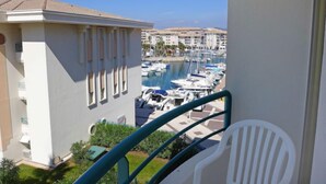 Ein Balkon mit Blick auf eine Marina, darunter Boote und Gebäude im Hintergrund.