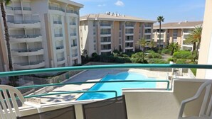 Ein Balkon mit Pool, weißen Stühlen und einem Tisch mit Teller und Glas.