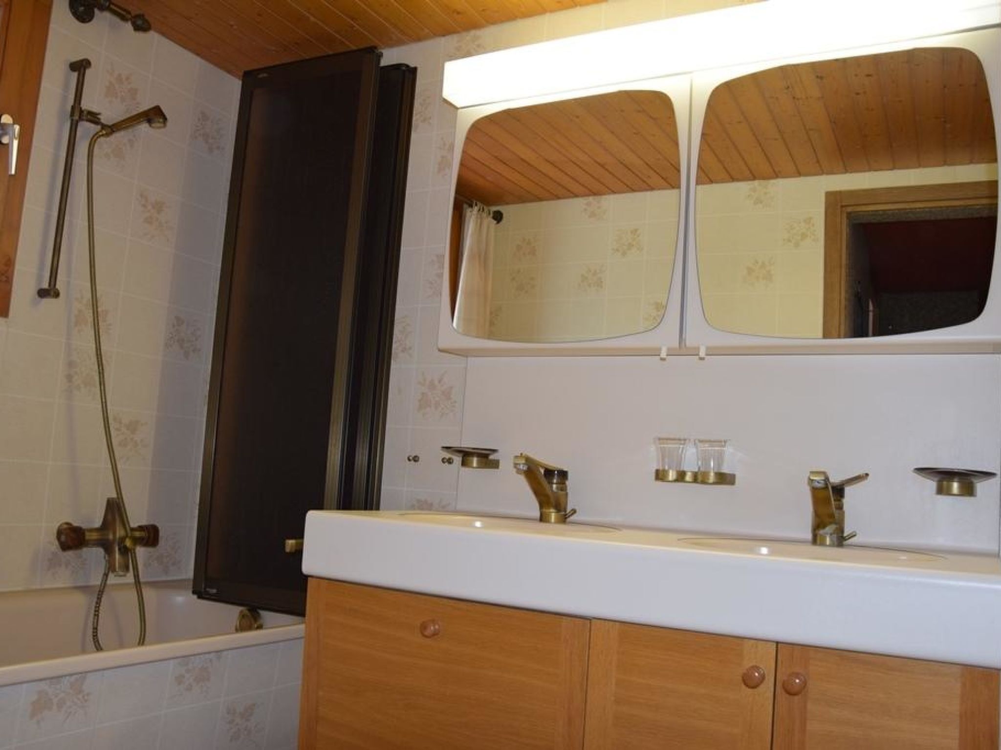 A bathroom with a wooden vanity, a mirror, a shower, and a bathtub.