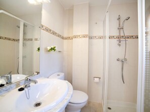 Un baño con lavamanos, inodoro y ducha blancos.
