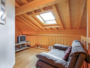 Une chambre confortable située sous les toits, avec un plafond en pente, un puits de lumière, une télévision et un canapé.