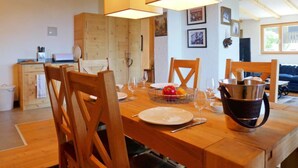 A dining area with wooden furniture, a table set for four, and a hanging light fixture. - Regina B9 by Interhome (Villars)