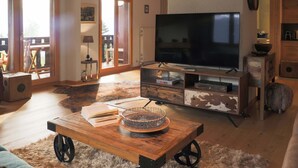 A spacious living room with a large flat-screen TV, wooden coffee table, and a fluffy rug. - Regina B9 by Interhome (Villars)