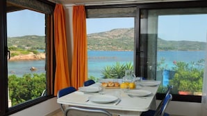 A dining area with a table set for two, overlooking a scenic coastal landscape. - Tritone by Interhome (Porto Istana)