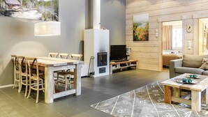 A modern living room with a wooden dining table, chairs, a fireplace, a television, and a sofa. - Sallan panparkstie 14 b by Interhome (Salla)