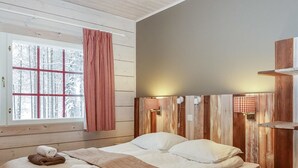 A cozy room with a bed, two bedside tables, a window with a view of snow-covered trees, and a red and white checkered curtain. - Sallan panparkstie 14 b by Interhome (Salla)
