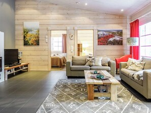 A cozy living room with a sofa, a coffee table, and a television.