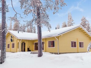 A yellow cabin with a snow-covered roof, surrounded by trees. - Sallan panparkstie 14 b by Interhome (Salla)