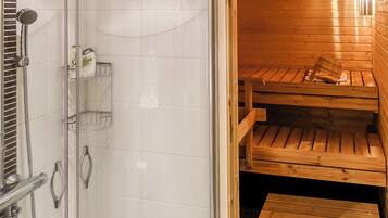 A sauna room with wooden benches and a glass door leading to a shower area.