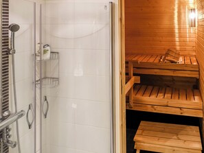 A sauna room with wooden benches and a glass door leading to a shower area. - Sallan panparkstie 14 b by Interhome (Salla)