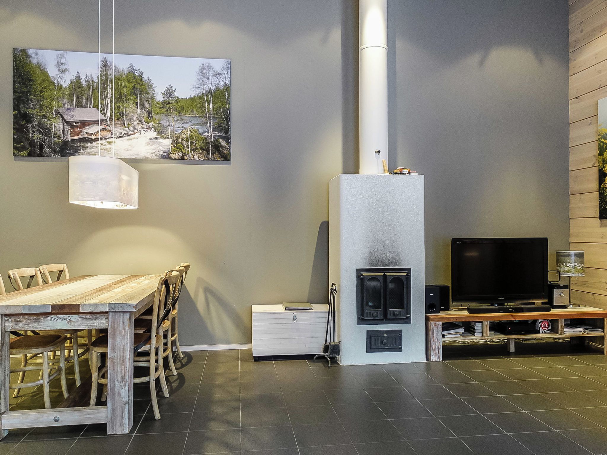 Moderni olohuone, jossa on takka, ruokapöytä tuoleineen, televisio ja taulu seinällä.