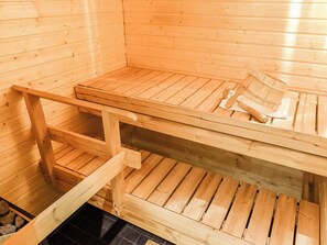 Eine Sauna mit hölzernen Bänken und einer Bank mit Handtuch und Holzgerät.