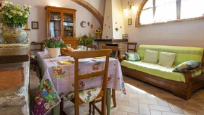 Una stanza accogliente con un tavolo da pranzo in legno, un divano verde e un muro in mattoni.
