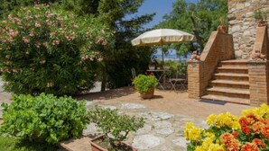 Un patio con un tavolo e sedie in pietra, una pianta in vaso e una scala in pietra che conduce a un edificio in pietra.