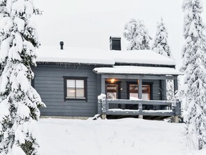 A house with a dark exterior, a porch with a railing, and a chimney.