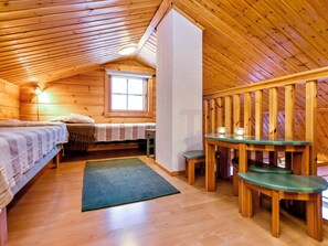 A cozy cabin with a lofted bedroom, a dining area with benches, and a small table.