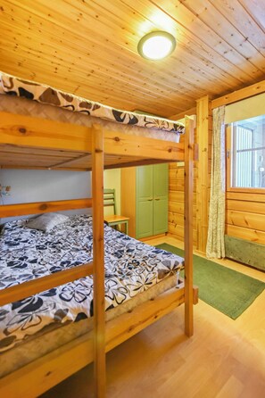 A bunk bed room with a wooden ceiling and a window.
