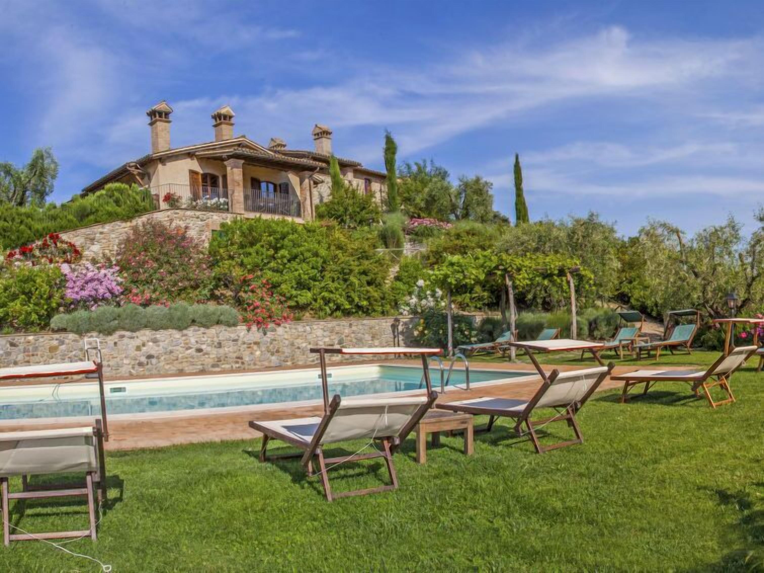 Un espace aménagé au bord de la piscine, avec des chaises longues et un mur en pierre.