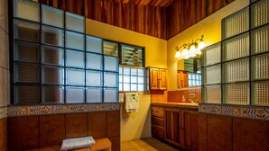 Une cuisine avec des meubles de rangement en bois, un évier et une fenêtre avec des stores.