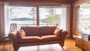 Una cabaña de madera con sofá, una mesa y vista a un lago.