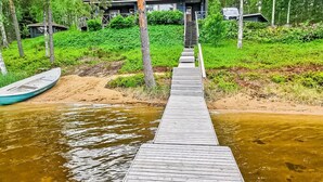 Un muelle de madera que conduce a una casa rodeada de vegetación.