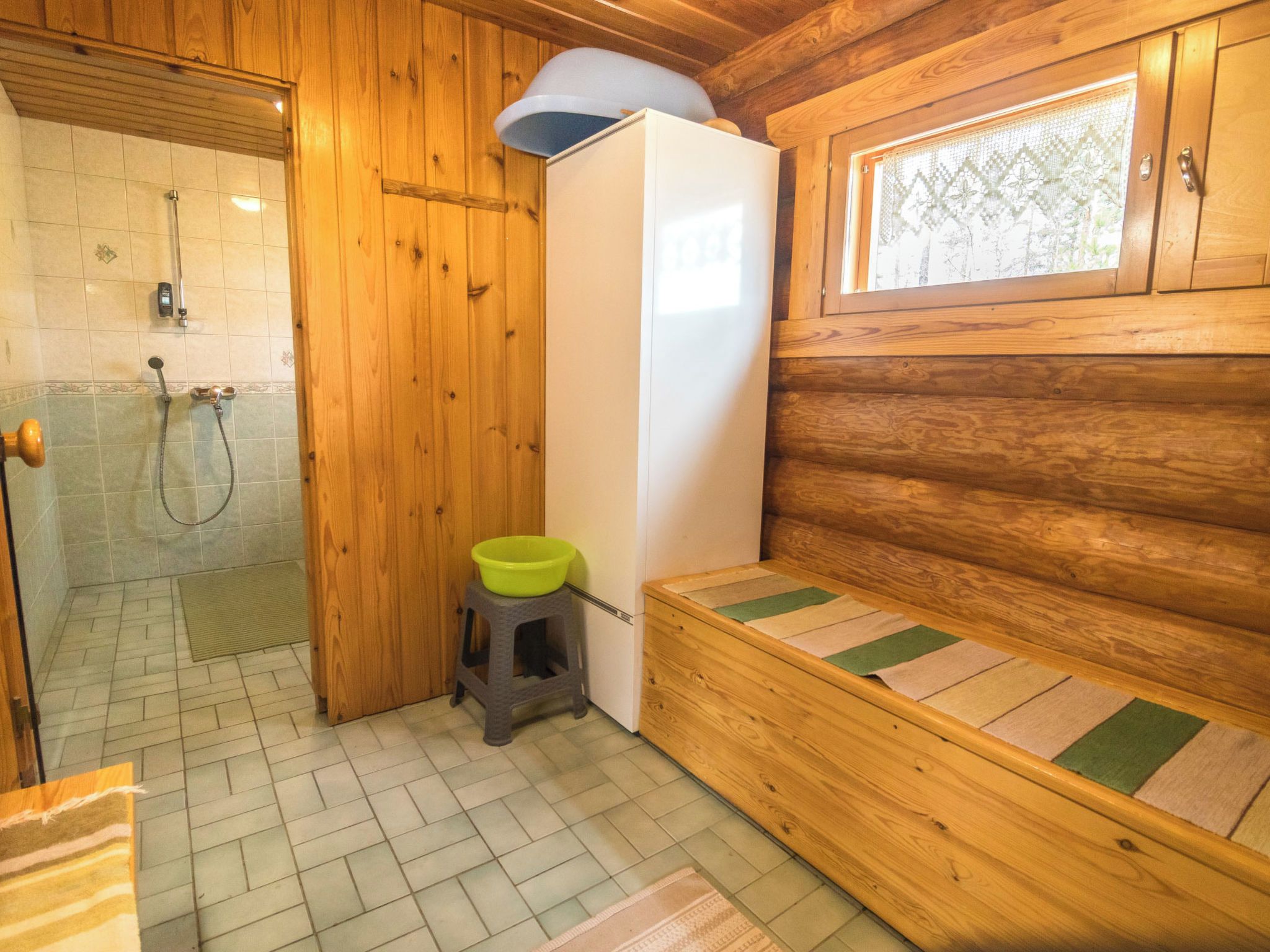 Ein Badezimmer einer Holzhütte mit Dusche, Toilette und einer Bank.