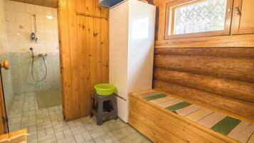 Ein Badezimmer einer Holzhütte mit Dusche, Toilette und einer Bank.