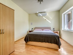 Een slaapkamer met een bed, een houten garderobe en een raam.