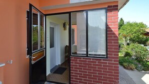 Une porte ouverte donnant sur une pièce avec vue sur un jardin et un mur de briques.