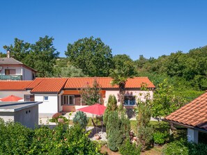 Un quartier résidentiel où les maisons se distinguent par leurs toits recouverts de tuiles rouges, le tout étant entouré d’une végétation luxuriante et d’arbres.