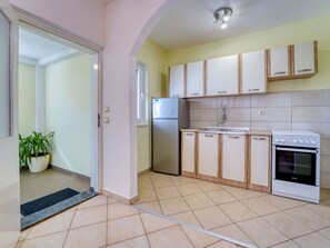 Een keuken met witte kasten, een koelkast, een spoelbak en een oven.