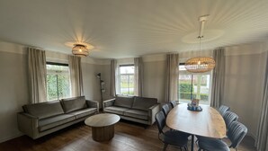 Ein geräumiges Wohnzimmer mit Holzboden, einem runden Esstisch und einer Sofagarnitur.