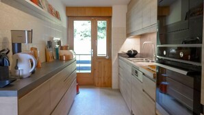 A modern kitchen with wooden cabinets, stainless steel appliances, and a tiled backsplash. - Schuss 23 by Interhome (Villars)