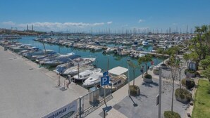 Un port de plaisance où sont amarrés de nombreux bateaux, un espace de stationnement et un ciel d’un bleu éclatant.
