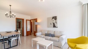 Un salon moderne comprenant un coin repas, un canapé, un fauteuil jaune et un tableau accroché au mur.
