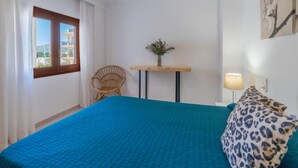 Une chambre à coucher avec un lit, une chaise, une petite table avec une plante et une lampe.