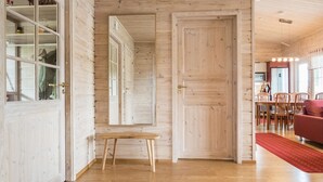 Un intérieur en bois comprenant un coin repas, une moquette rouge et un banc en bois.