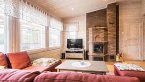 Un salon chaleureux avec une cheminée, des murs en bois et un téléviseur.