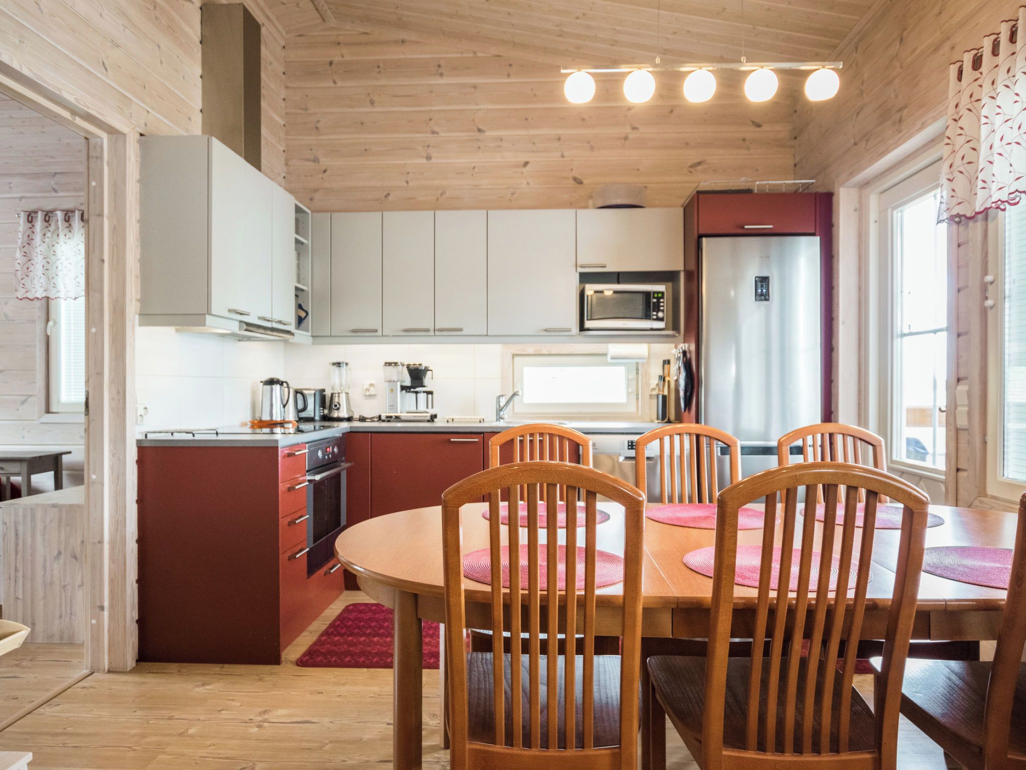 A kitchen with wooden cabinets, a microwave, a refrigerator, and a dining area with a table and chairs.