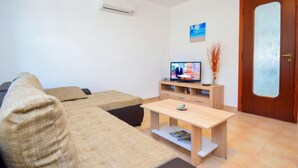 Una sala de estar con un sofá, un televisor, una mesa de centro de madera y una puerta.