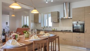 Una cocina moderna con armarios de madera, horno empotrado e iluminación colgante.