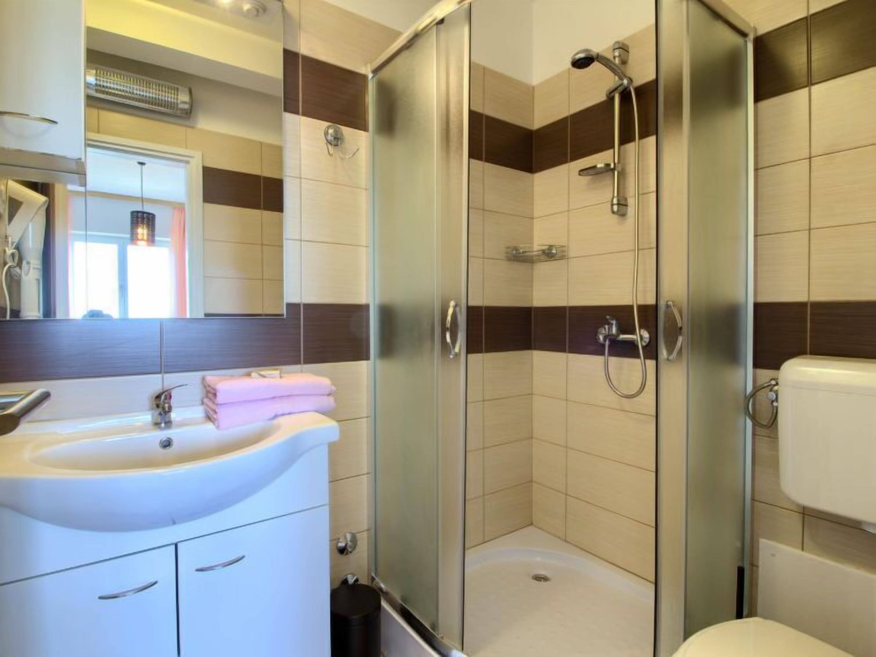 Une salle de bain moderne avec une douche à parois de verre, un lavabo blanc et des toilettes.