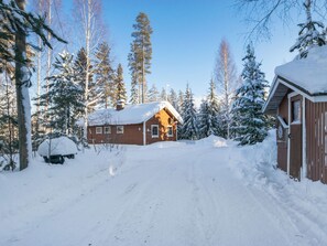 Eine Hütte, umgeben von schneebedeckten Bäumen, mit blauem Himmel.