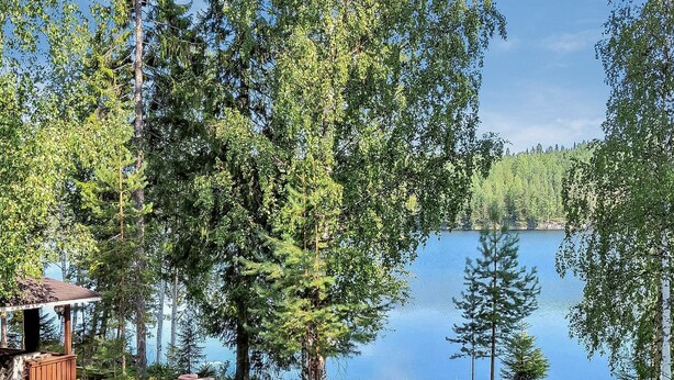 A lakeside cabin with a wooden deck and a view of the lake.