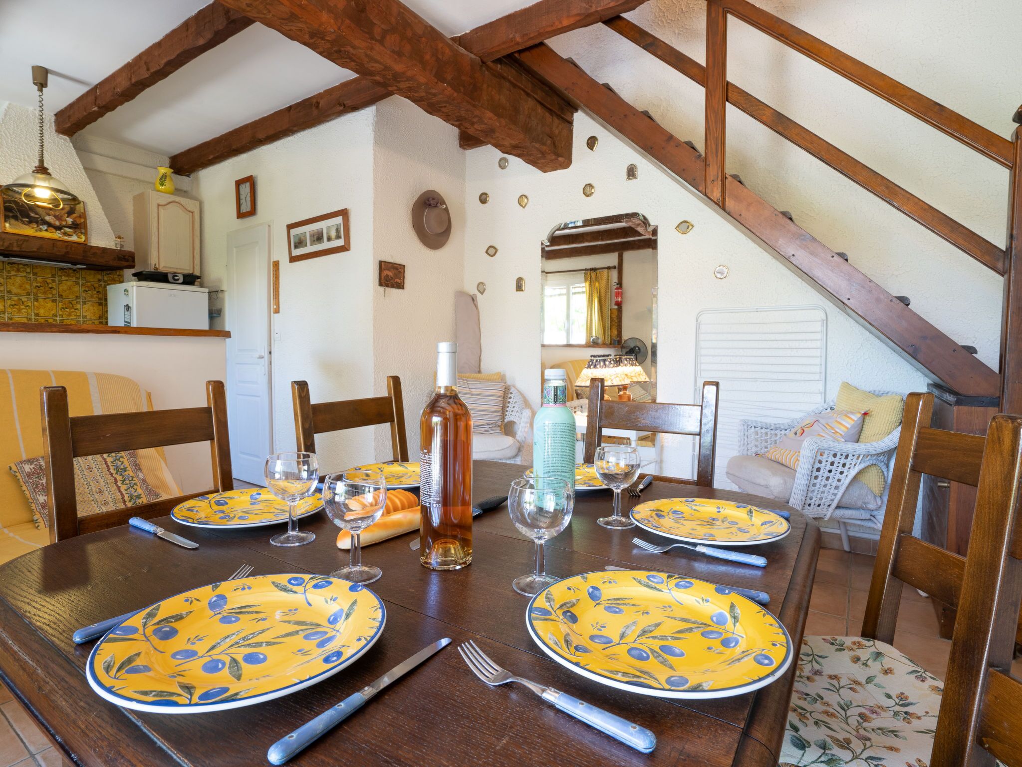 Une table à manger dressée avec des assiettes jaunes, des verres à vin et des couverts.