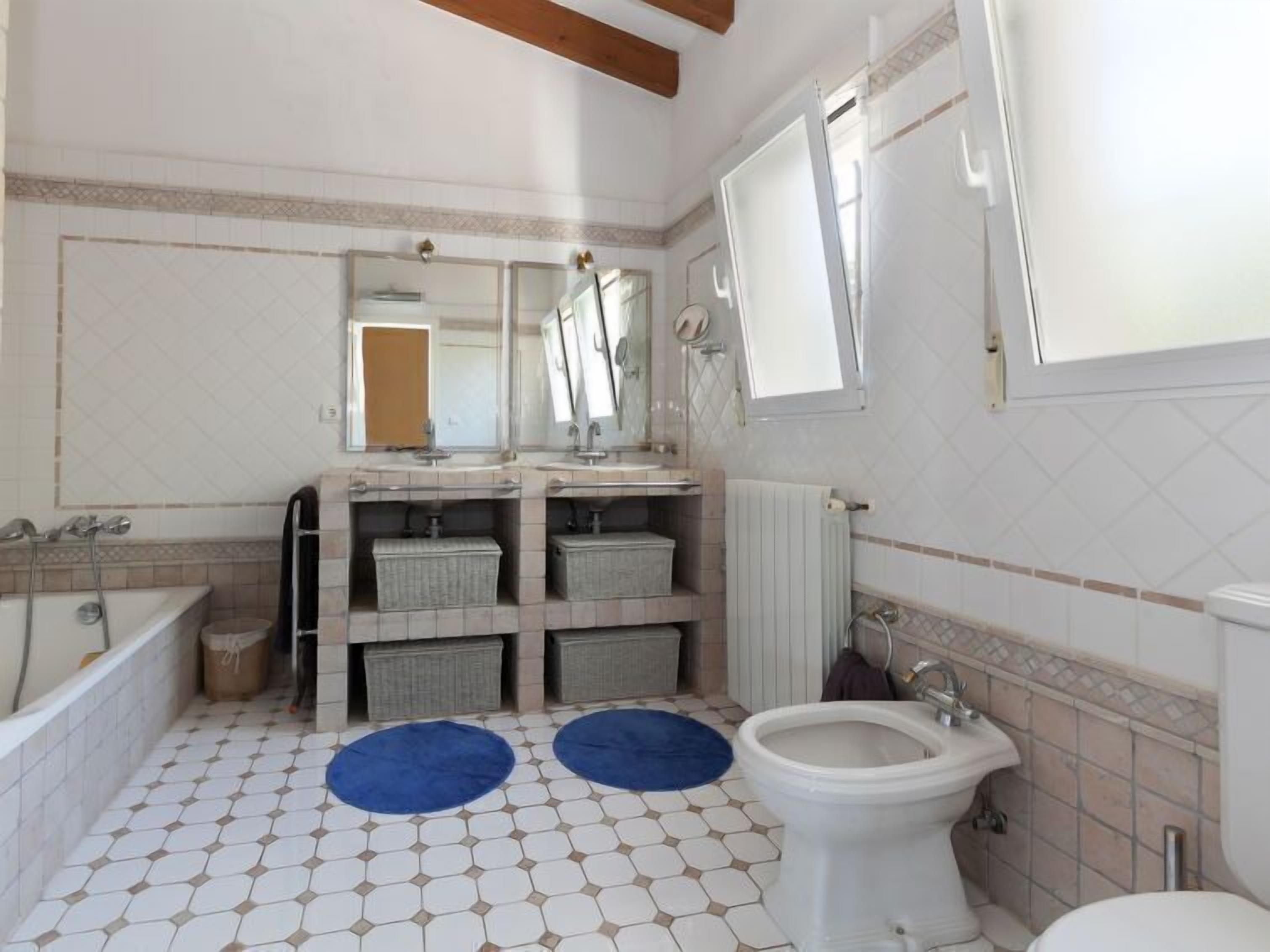 A bathroom with a bathtub, two sinks, a toilet, and a large mirror.
