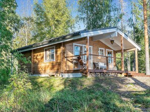 A wooden cabin with a porch, multiple windows, and outdoor seating. - Lahdenpohja, vaikon loma 7 by Interhome (Kaavi)