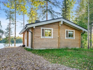 A wooden cabin with a covered porch, a small deck, and a view of a lake. - Lahdenpohja, vaikon loma 7 by Interhome (Kaavi)